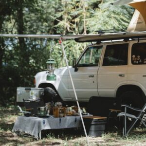 Camper offroader with roof top tent and awning camping in nature among green trees in sunny day